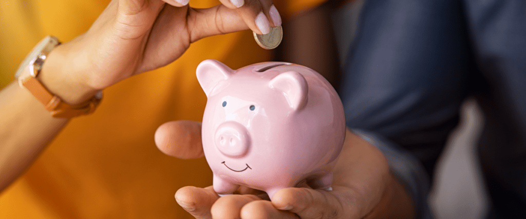 A lady putting money in her piggy bank.